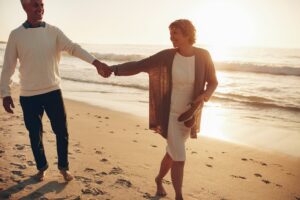 Senior couple walking on the beach together at sunset