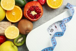 Scales, measuring tape and vegetarian food on gray background